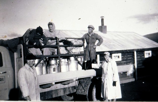 Mjølkebilen klar for avgang frå Tollevshaugen ved sekstida om morgonen, truleg ein gong på 1950-talet. Ståande på lasteplanet, sjåføren i mange år, Magne Rudiløkken. Dei andre er turister som skal vera med bilen. Og dei det ikkje er plass til inni førarhuset må sitja oppå spanna. 