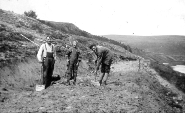 Vegparsell under bygging med spade, på 1930-talet. Kvar sætereigar fekk pådelt ein slik parsell (vegstykke) etter som dei gjekk fram med vegarbeidet. Dette er ved Storberget. Ein kan skimte Grimsdalshytta mot Tverådalen i bakgrunnen. Dette er parsellen til Søre Bjørnsgard, og karane er frå vinstre: Laurits Bergseng, Hans Helge Bjørnsgard og Anton Jøndal. Før vegen vart bygd her, køyrde dei på andre sida av elva utover til forbi campingplassen ved Tverråe.